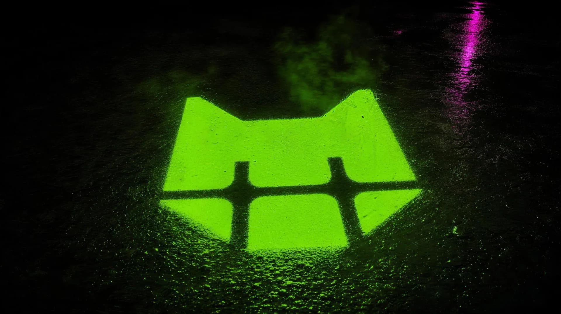 The FatCat mark spray-painted in glowing neon green on dark wet asphalt